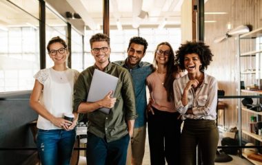 Portrait of creative business team standing together and laughing. Multiracial business people together at startup.